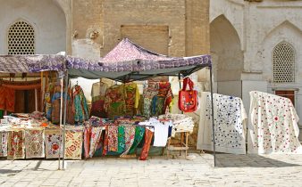 an outdoor market with cloths and umbrellas for sale